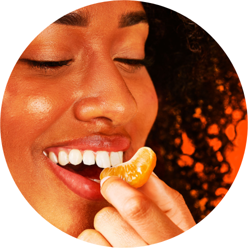 A woman biting a peeled piece of Peelz seedless California mandarins.