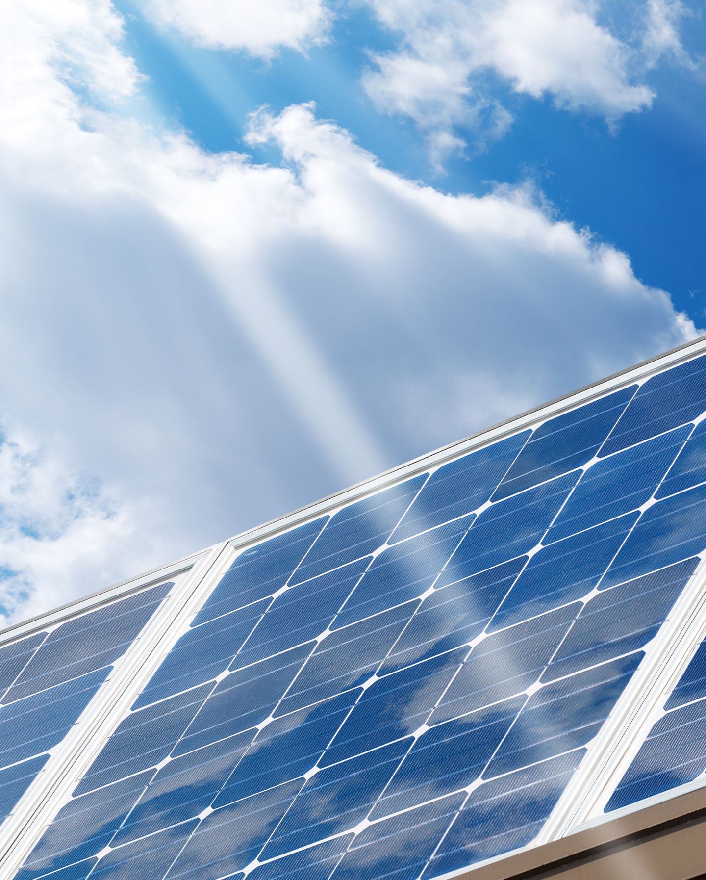 An image of solar panels with a blue cloudy sky