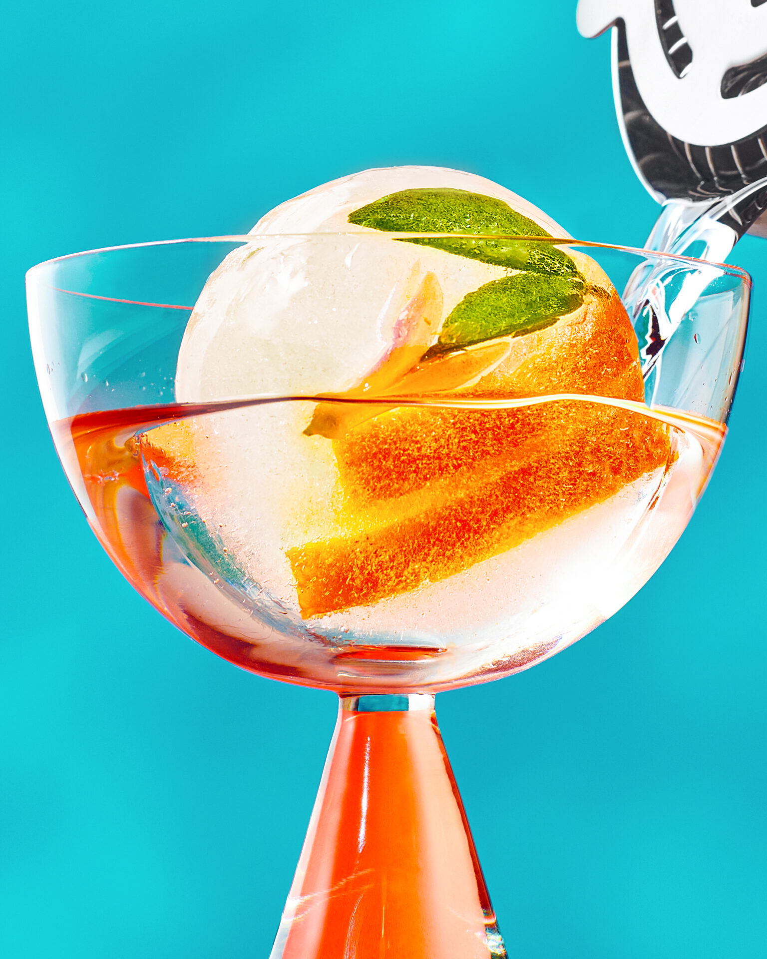 A cocktail glass with a citrus ice cube