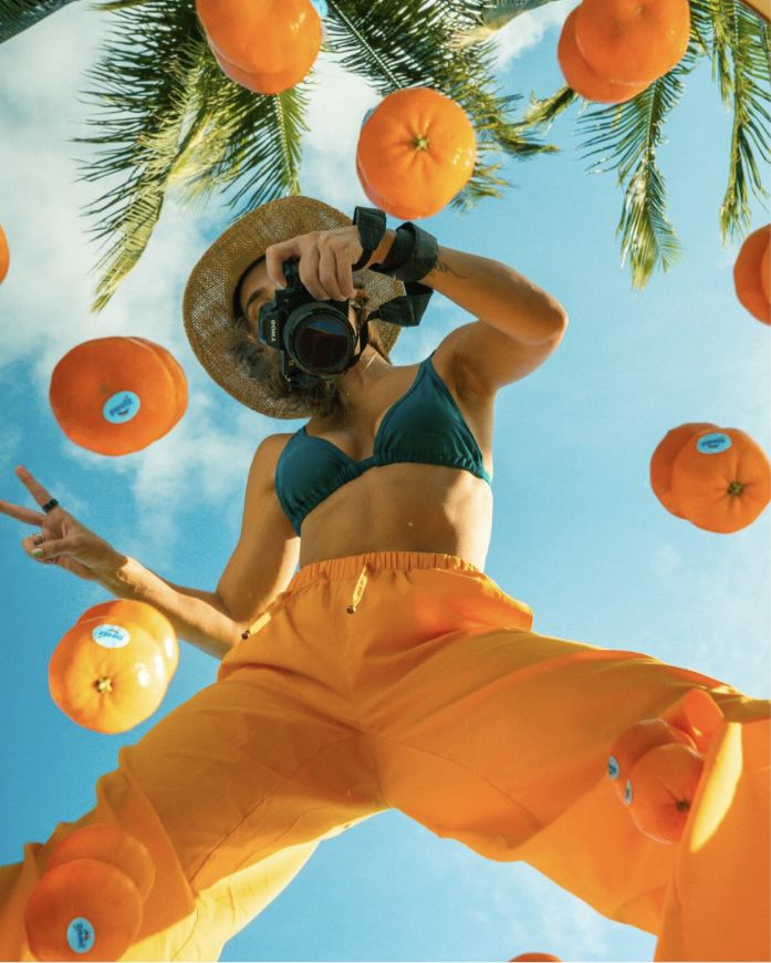 A woman with a camera taking of photo of Peelz seedless California mandarins